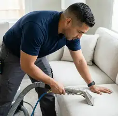 Professional upholstery cleaning technician using an extraction wand to deep-clean a fabric sofa, Norfolk, VA.
