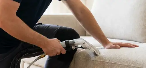 Professional upholstery cleaner deep-cleaning a fabric sofa with a handheld extraction tool, Norfolk, VA.